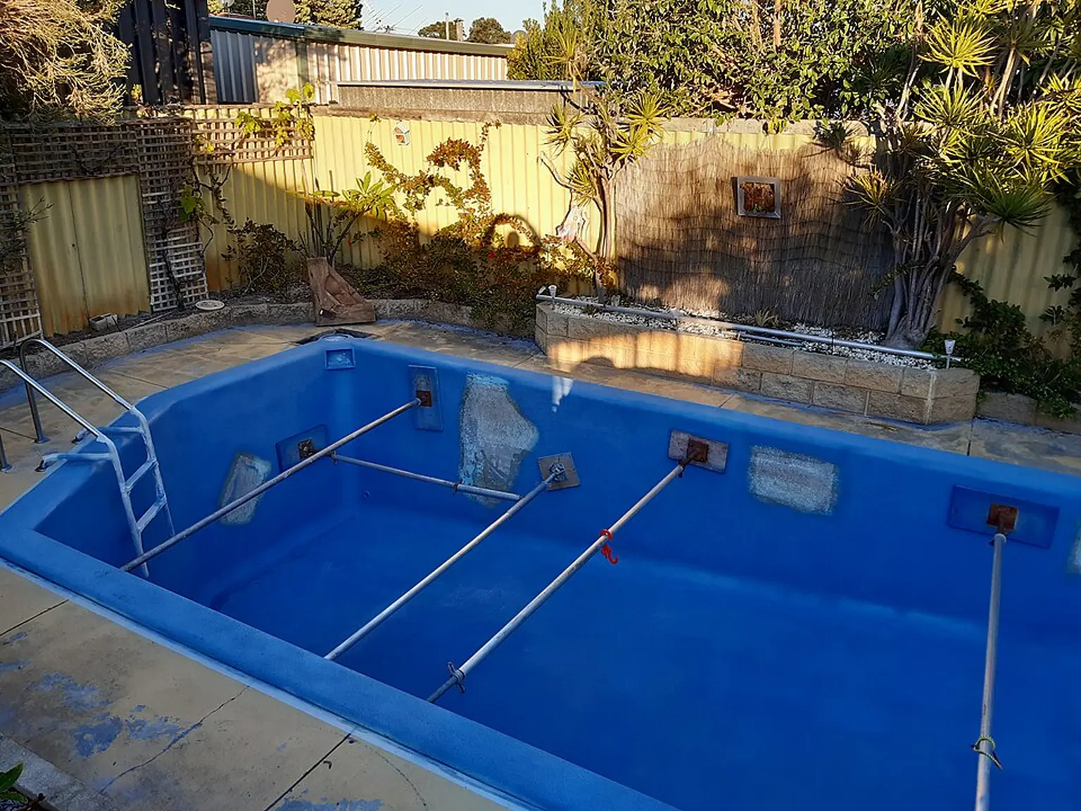 Drained fibreglass pool during refurbishment in Perth, with wall patches and temporary bracing